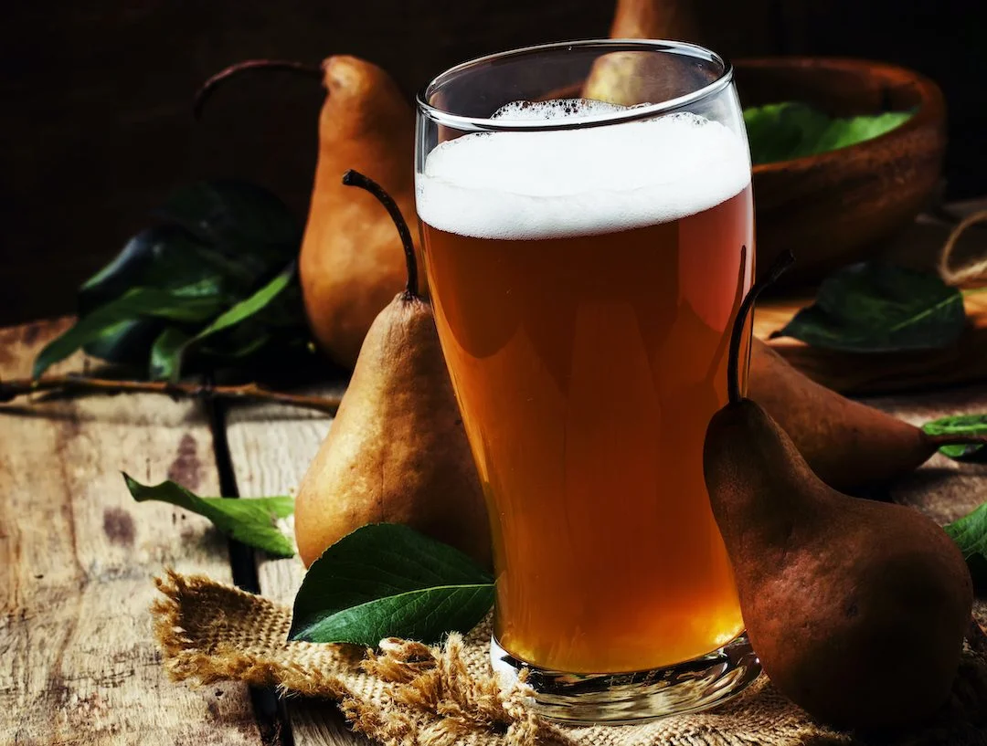 Pear cider in a large beer glass, old wooden background, selective focus