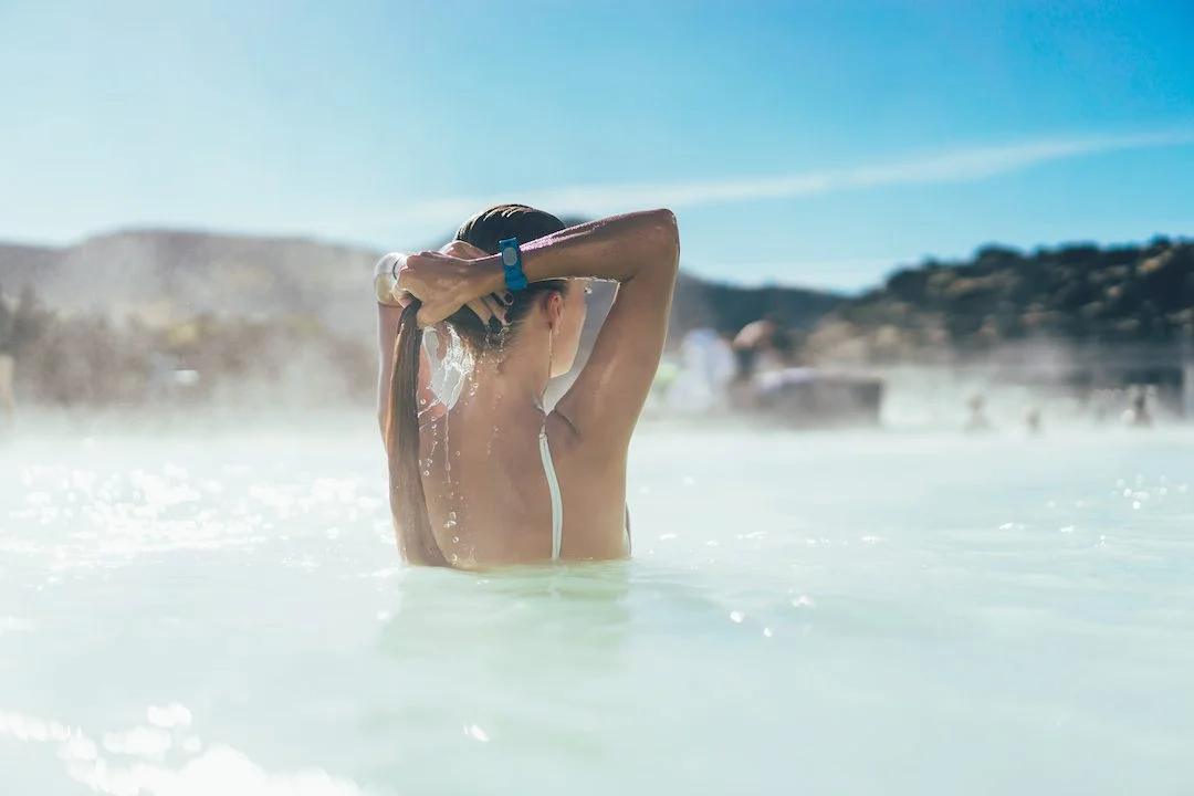 rear view of young woman relaxing in hot pool