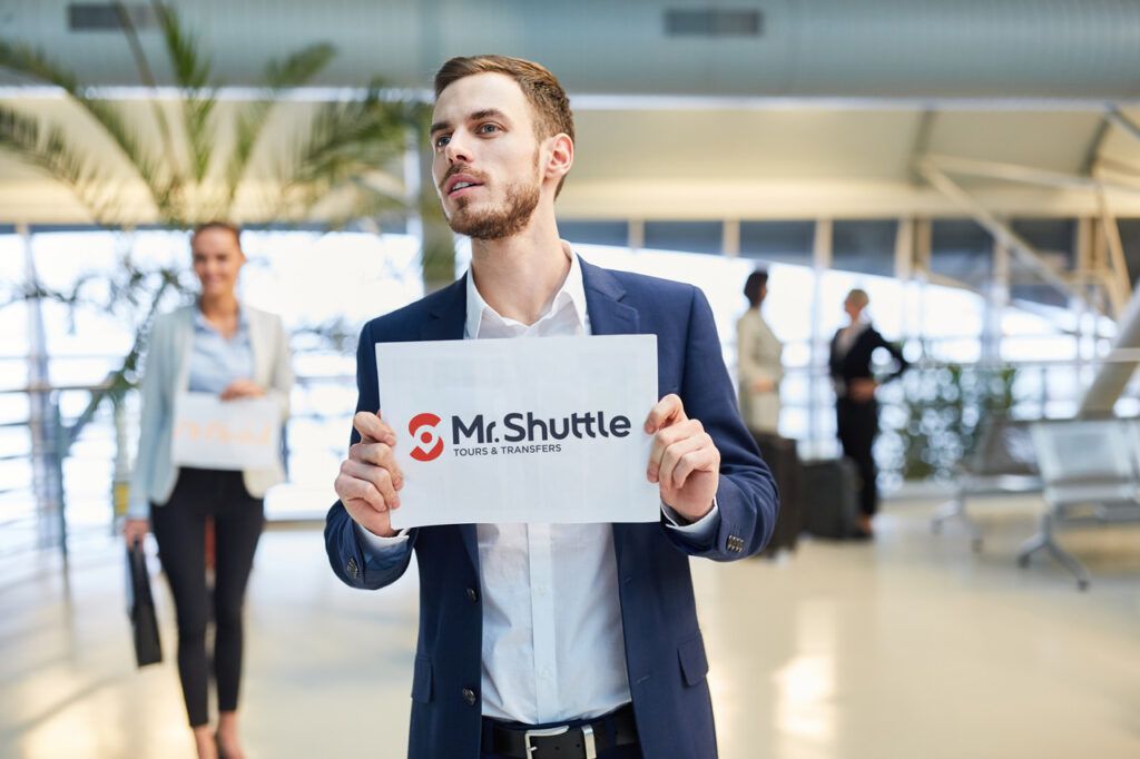 The driver of MrShuttle is waiting for a customer with welcome board