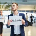 The driver of MrShuttle is waiting for a customer with welcome board