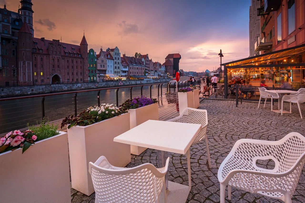 Old town in Gdansk with historical port crane over Motlawa river at rainy sunset, Poland.