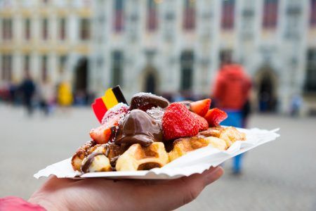 Belgium waffle with chocolate sauce and strawberries, Bruges city background, Belgium.