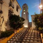 Balconies looks over the steps and flowers leading up to a tower in the old town of Estepona, Costa del Sol Spain, at twilight