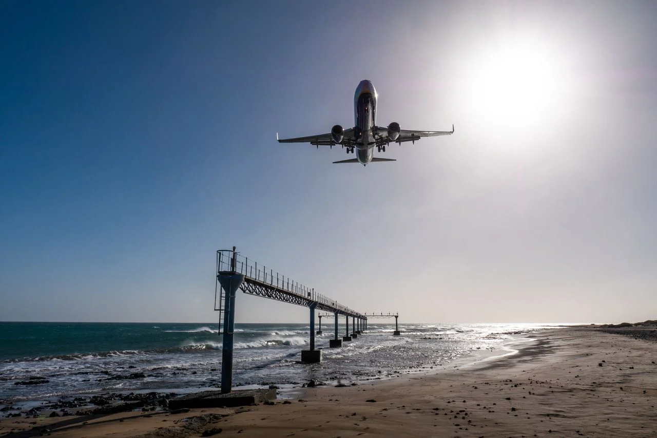 Plane lands almost at airport Lanzarote, seen from beach towards the sea