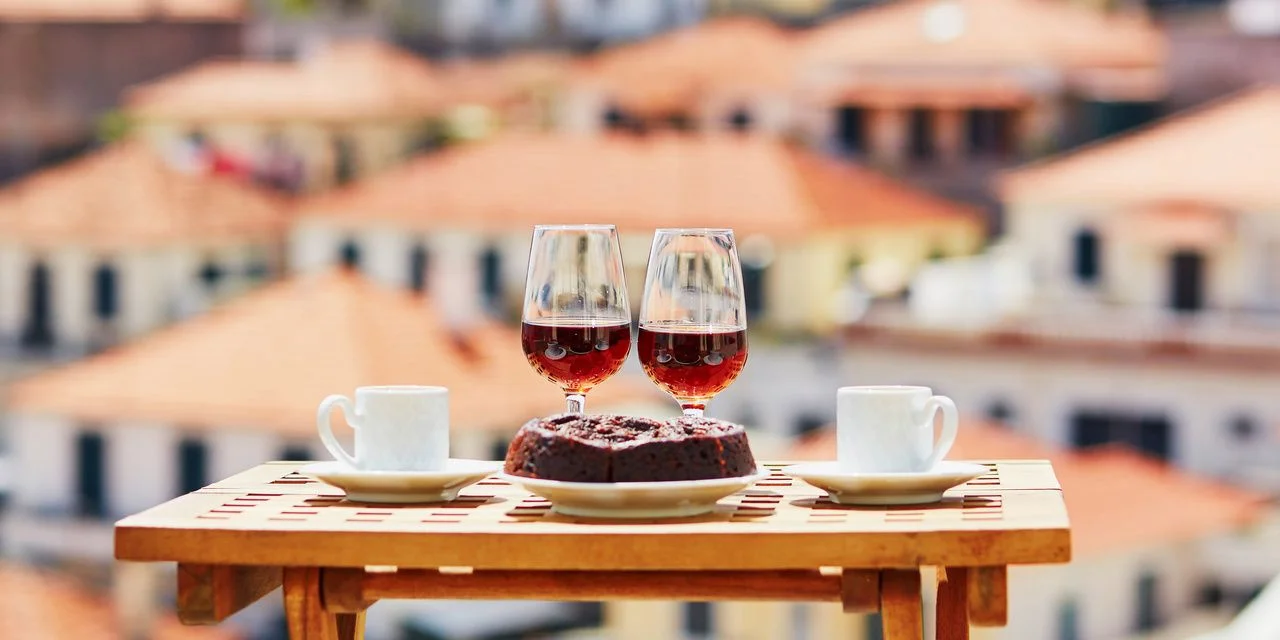 Two glasses of Madeira wine with view to Funchal town, Madeira, Portugal