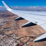 Wing of airplane taking off Fuerteventura Airport, above city.