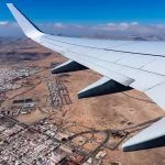 Wing of airplane taking off Fuerteventura Airport, above city.