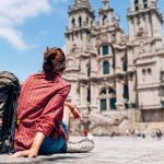 Woman backpacker piligrim siting on the Obradeiro square (plaza) in Santiago de Compostela