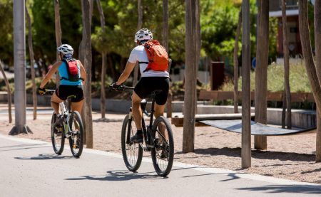 A couple of cyclists go down the bike path in Madrid Rio Park, Madrid, Spain