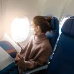 A young woman wearing face mask is traveling on airplane
