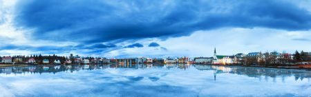 Beautiful panorama of the skyline cityscape of Reykjavik, reflected in lake Tjornin at the blue hour in winter