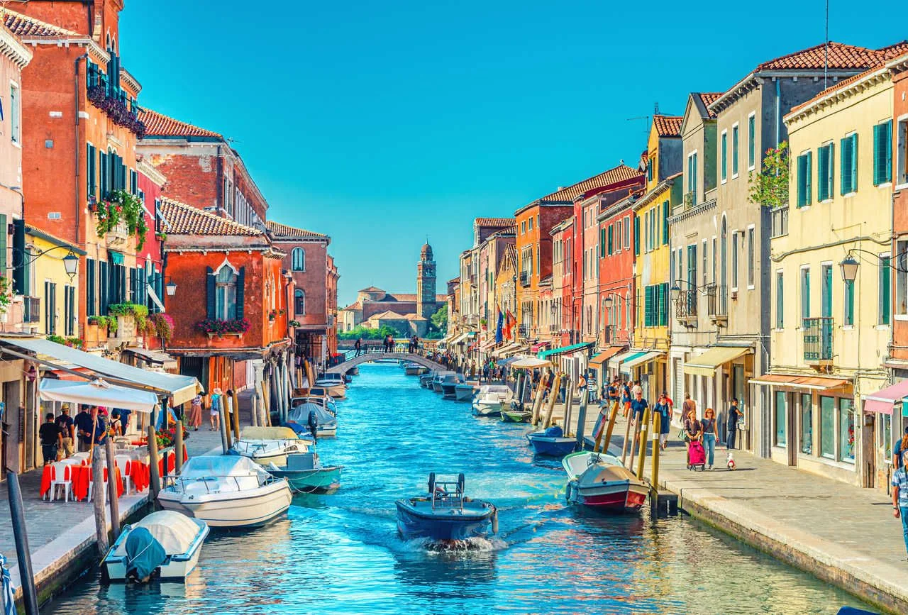 Murano islands, bridge across water canal, boats and motor boats, colorful traditional buildings, Venetian Lagoon, Veneto Region, Northern Italy.