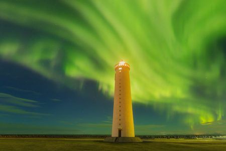 This beautiful northern lights or aurora borealis in Iceland was taken at or around lighthouse near Keflavik during a winter night. Green northern lights. Starry sky with polar lights.