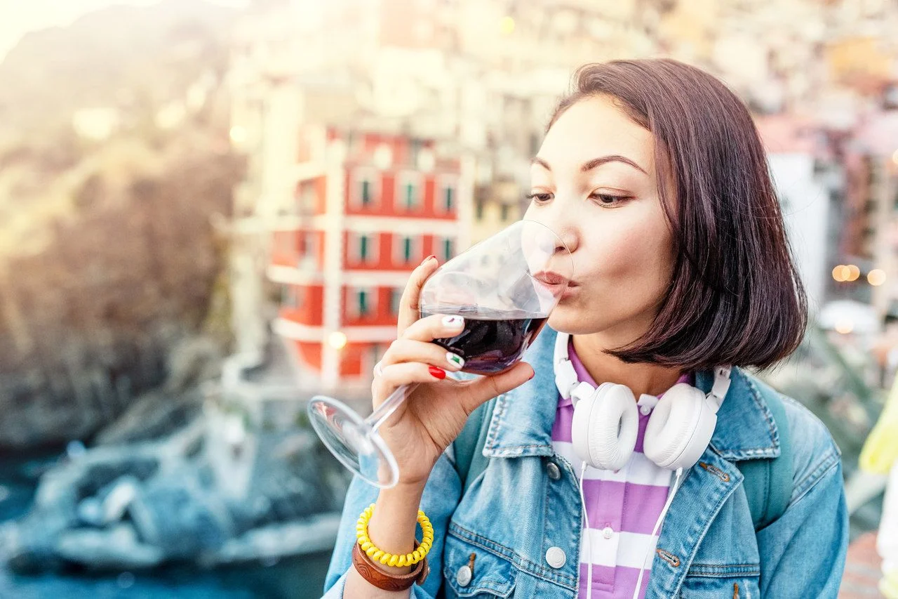 Traveler woman tasting red wine in Italy, famous Cinque Terre and Riomaggiore region.