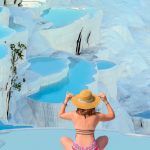 Young girl looking at travertine pools and terraces in Pamukkale – Young girl sunbathing and sitting front travertine pools – Cotton castle in southwestern Turkey
