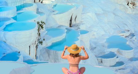 Young girl looking at travertine pools and terraces in Pamukkale – Young girl sunbathing and sitting front travertine pools – Cotton castle in southwestern Turkey