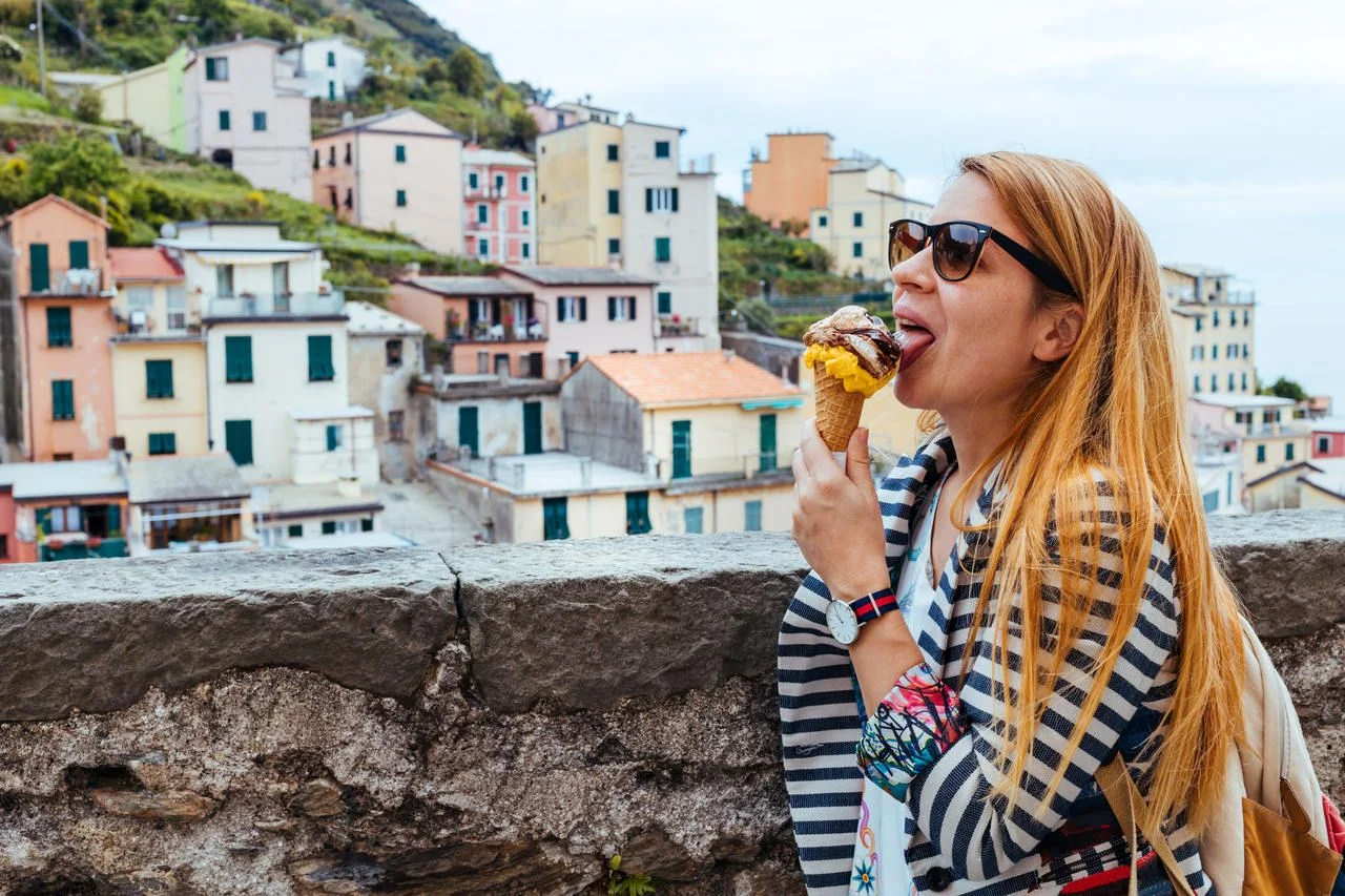 Young woman eating icecream in Manarola, Cinque Terre, Liguria, Italy