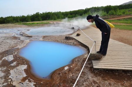 Young woman is amazed of Geyser area, trip on Iceland