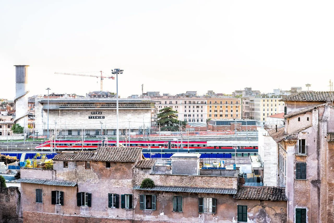 Aerial view on Roma Termini Rome main central railway station in Italy with railroad tracks and passenger red trains moving during sunset