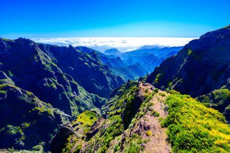 Beautiful hiking trail from Pico do Arieiro to Pico Ruivo, Madeira island. Footpath PR1 – Vereda do Areeiro. On sunny summer day above the clouds. Portugal.