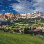 Cortina d’Ampezzo town panoramic view with alpine green landscape and massive Dolomites Alps in the background. Province of Belluno, South Tyrol, Italy.