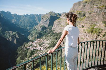 Girl at Viewpoint Eira do Serrado looking to Curral das Freiras village in the Nuns Valley in beautiful mountain scenery, municipality of Câmara de Lobos, Madeira island, Portugal.