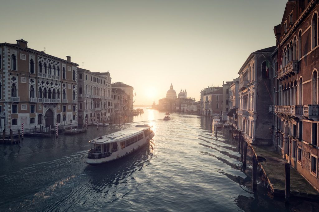 Misty sunrise on the Grand Canal in Venice with a ferry heading towards the Basilica di Santa Maria della Salute
