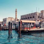 Skyline view of Dubai Creek with traditional boats and piers. Sunny summer day. Famous tourist destination in UAE.