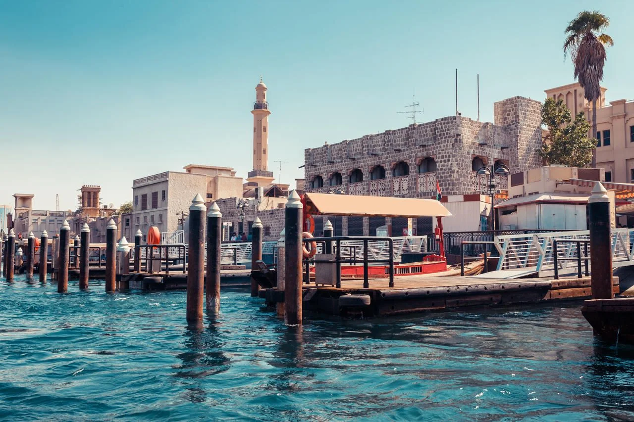 Skyline view of Dubai Creek with traditional boats and piers. Sunny summer day. Famous tourist destination in UAE.