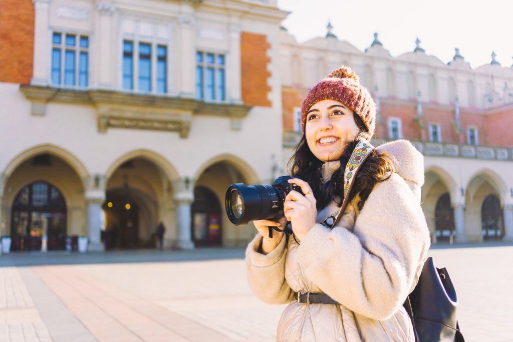 A woman traveler with a camera standing in front of the Cloth Hall in Krakow