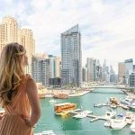 Woman in Dubai Marina, United Arab Emirates. Attractive lady wearing a long dress admiring Marina harbor daylight view