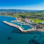 Aerial bird’s eye view of Latchi port, Akamas peninsula, Polis Chrysochous, Paphos,Cyprus. Latsi harbour with boats and yachts, fish restaurant, promenade, beach tourist area and mountains from above