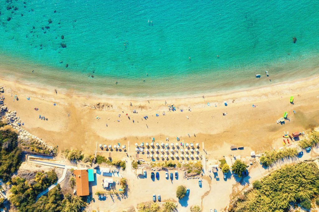 Aerial view of Coral Bay beach – popular beach with clear sea water and comfortable sandy beach, many tourists, sunbeds with umbrellas in Peyia village, Cyprus.