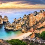 Beautiful Camilo Beach in Lagos, Portugal, with stunning cliffs and a blue ocean colorfully lit at sunrise
