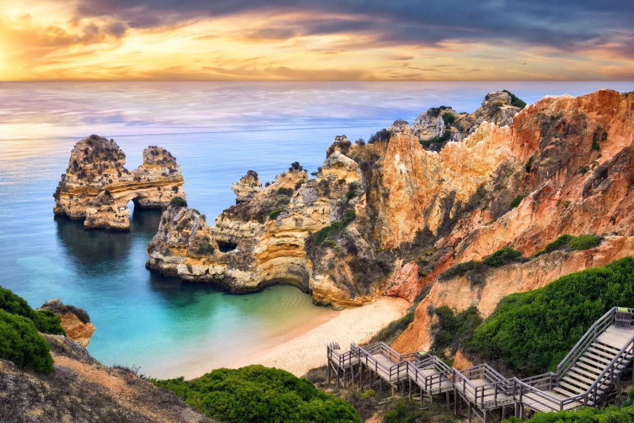 Beautiful Camilo Beach in Lagos, Portugal, with stunning cliffs and a blue ocean colorfully lit at sunrise