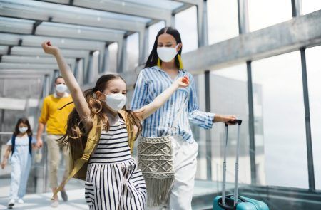 Family with two children going on holiday, wearing face masks at the airport during Covid 19