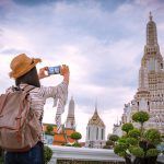 Asian female tourists take photos with smartphone at Wat Arun temple on vacation in Bangkok Thailand.