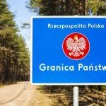 Border with emblem of the Poland. Road and forest in background.