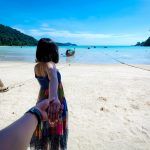 The back of the girl holding the hand of a young man inviting to sea at Moken village, Surin Island National Park Kuraburi District, Phang Nga Province, Southern Thailand.