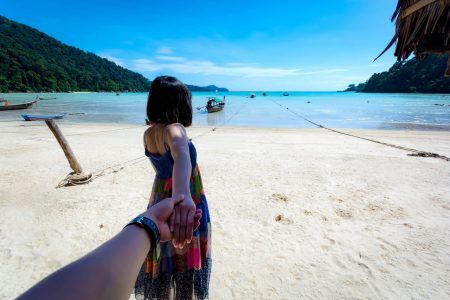 The back of the girl holding the hand of a young man inviting to sea at Moken village, Surin Island National Park Kuraburi District, Phang Nga Province, Southern Thailand.