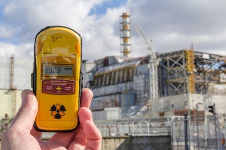 UKRAINE. Chernobyl Exclusion Zone. – 2016.03.19. Dosimeter and Nuclear Power Plant on the background