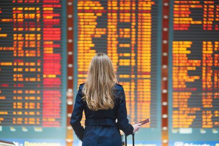 Young,Woman,In,International,Airport,Looking,At,The,Flight,Information