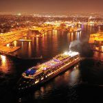 Aerial drone night shot of beautiful illuminated port of Piraeus and huge cruise liner departing to Aegean popular destinations, Attica, Greece