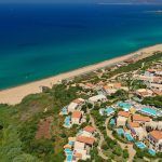 Aerial drone panoramic photo of famous sandy deep turquoise – blue exotic beach and famous luxury paradise resort of Costa Navarino in Messinia, Peloponnese, Greece
