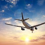 Airplane in the sunset sky flight travel transport airline background concept.