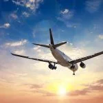 Airplane in the sunset sky flight travel transport airline background concept.