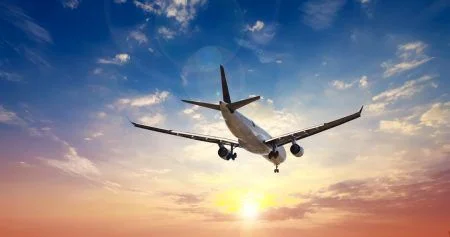 Airplane in the sunset sky flight travel transport airline background concept.