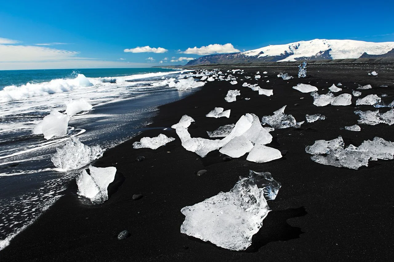 Beautiful beach in the South of Iceland with a black lava sand is full of icebergs from glaciers not far away