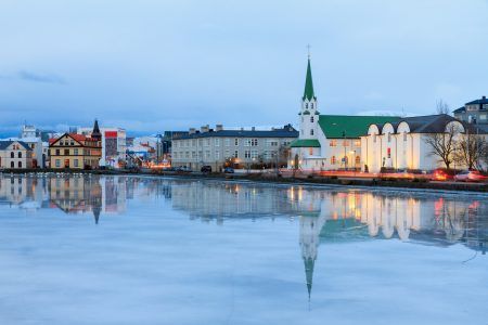 Beautiful reflection of the cityscape of Reykjavik and the Free church in lake Tjornin at the blue hour in winter