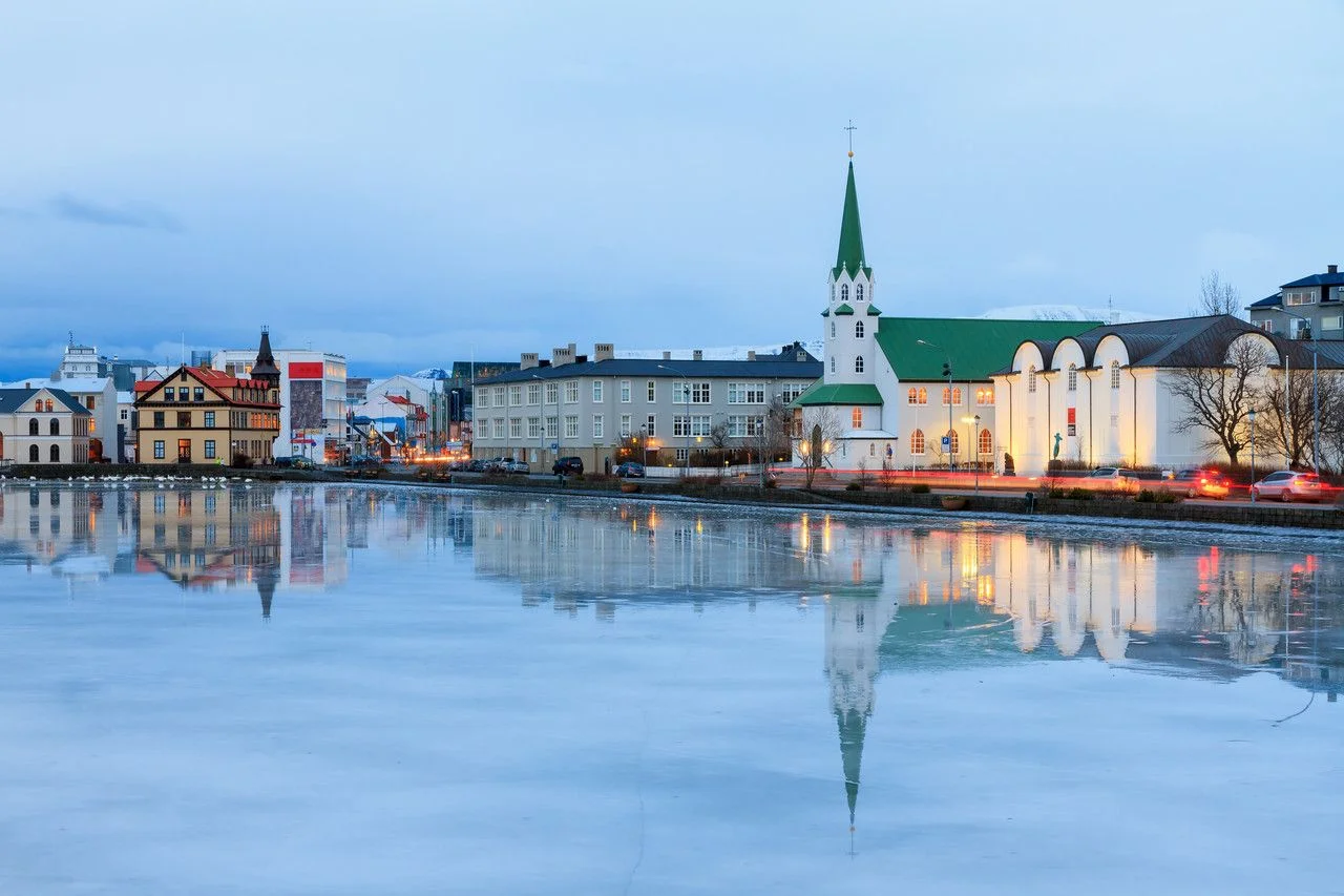 Beautiful reflection of the cityscape of Reykjavik and the Free church in lake Tjornin at the blue hour in winter